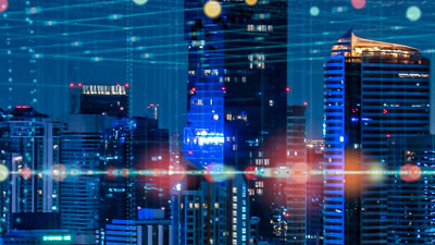 A futuristic city skyline at night features illuminated skyscrapers, overlayed with digital lines and abstract glowing dots, embodying technology and managed spectrum connectivity.